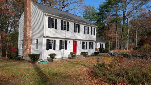 White colonial with black shutters and a red door