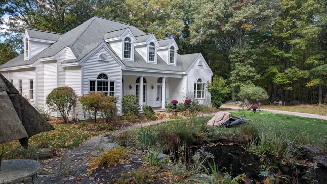White cape with dormers above a stone garden