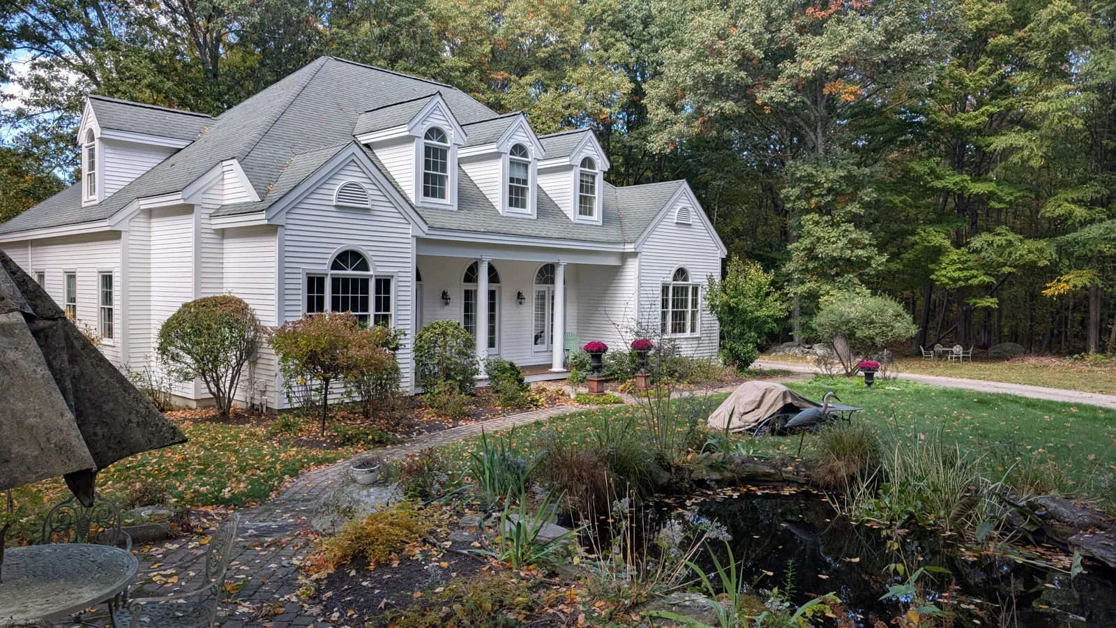 White cape with dormers above a stone garden