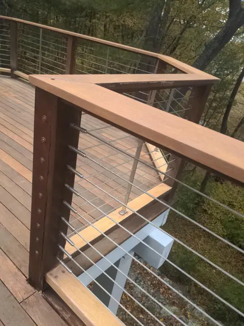 Stained deck rail corner with cable railing