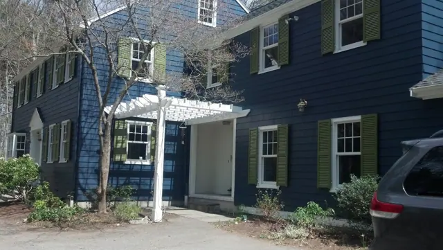 Navy colonial with green shutters and a white pergola