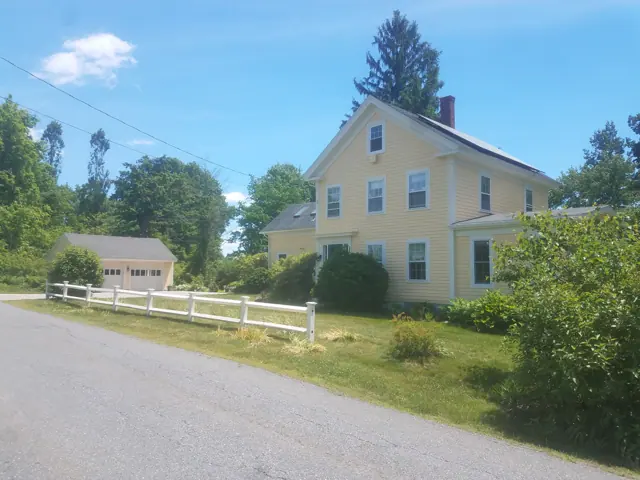 Yellow farmhouse behind a white fence