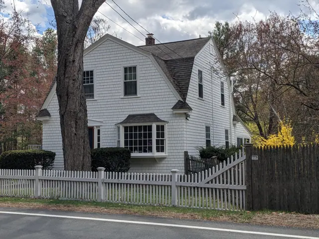 White Dutch colonial behind a picket fence